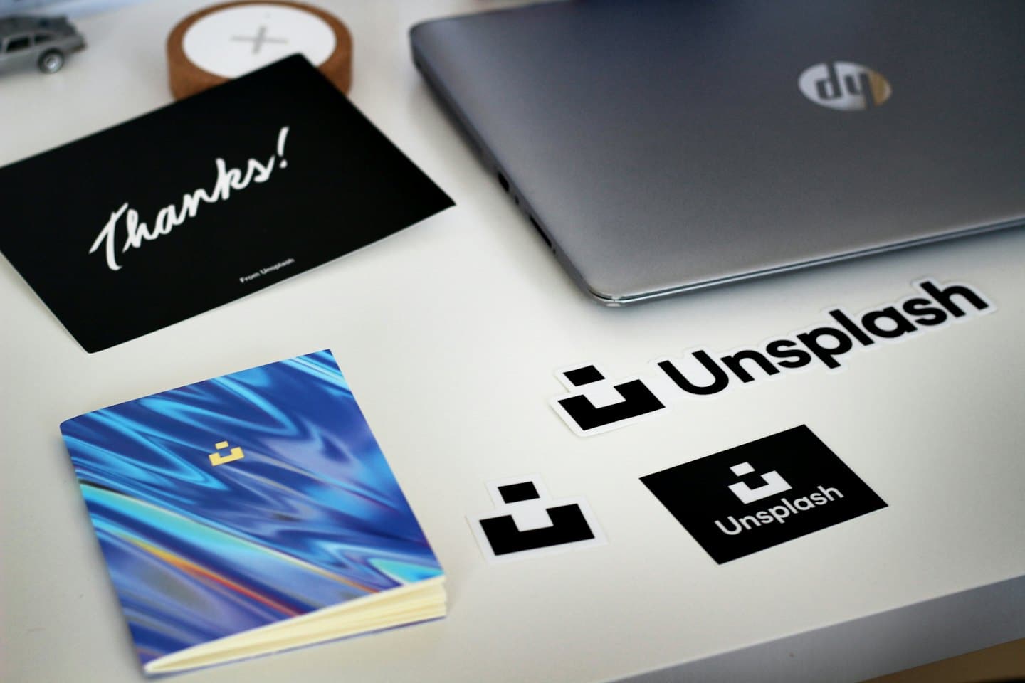 Branded laptop stickers and notebooks arranged on a white desk.